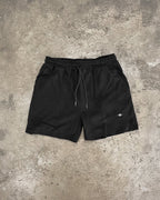 Black shorts with a small white logo on a gray concrete surface