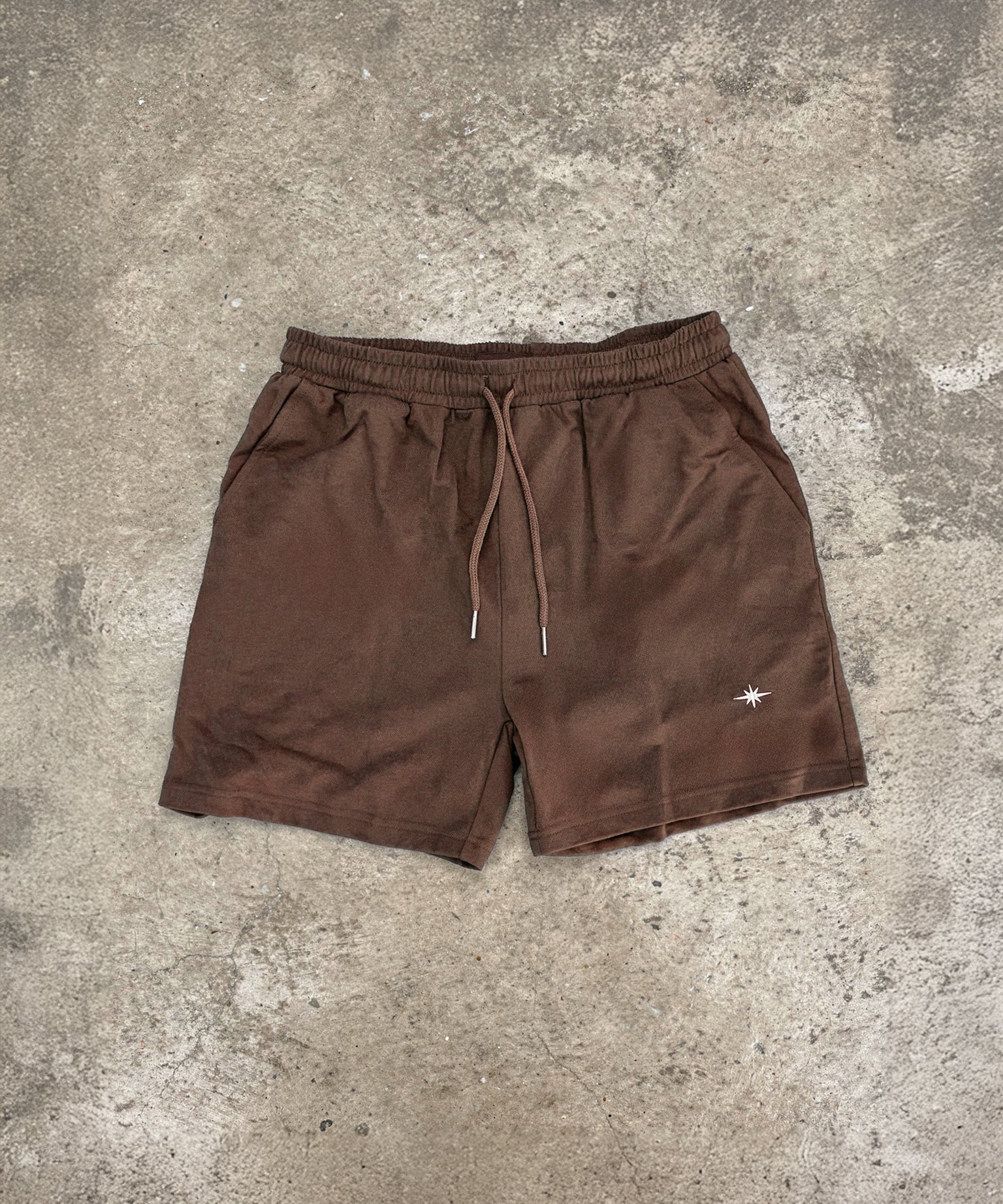 Espresso brown Sol Dept. cotton gym shorts on a gray concrete surface