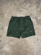 Forest green Sol Dept. cotton gym shorts on a gray concrete surface