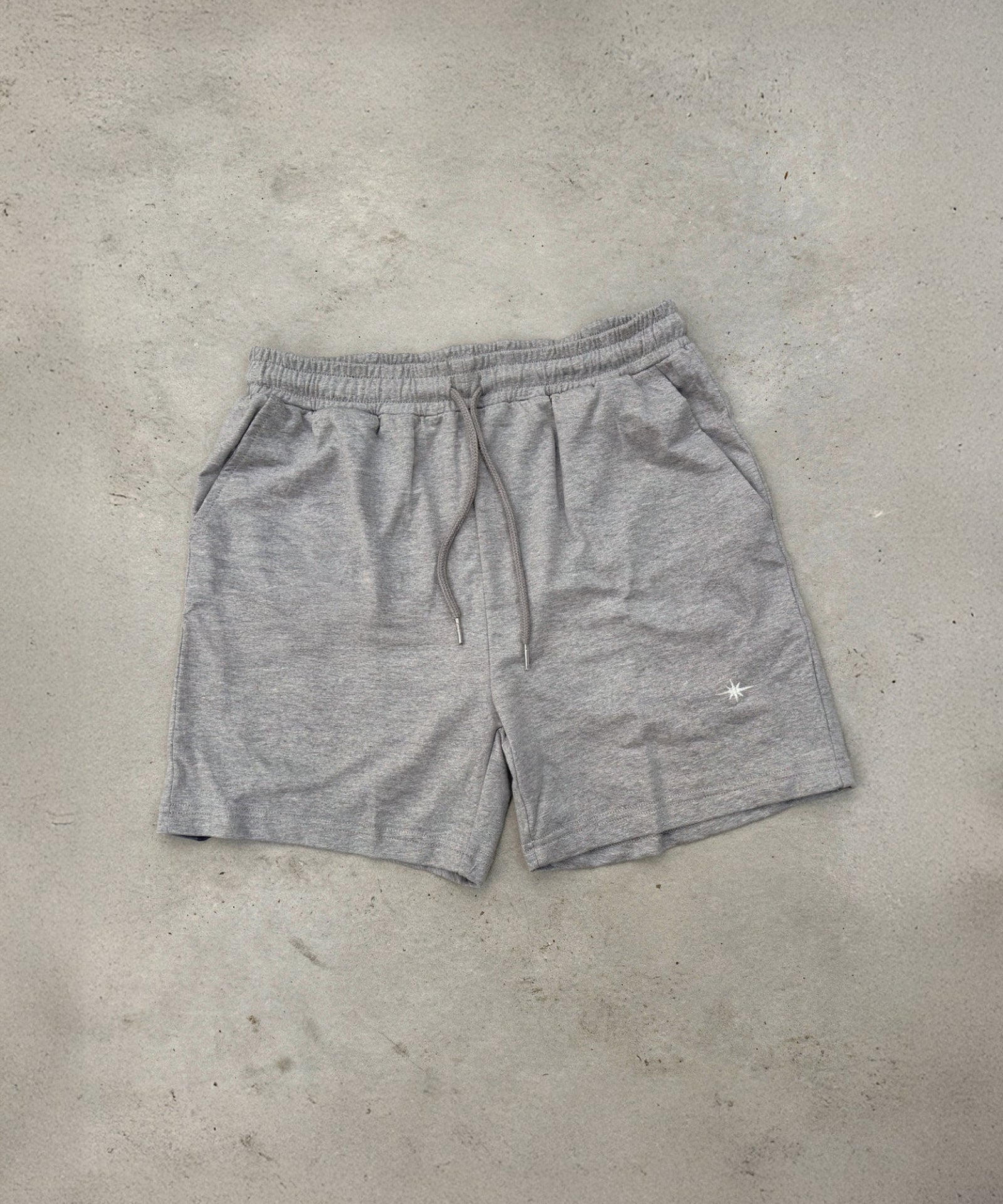 Ash grey Sol Dept. cotton gym shorts on a gray concrete surface