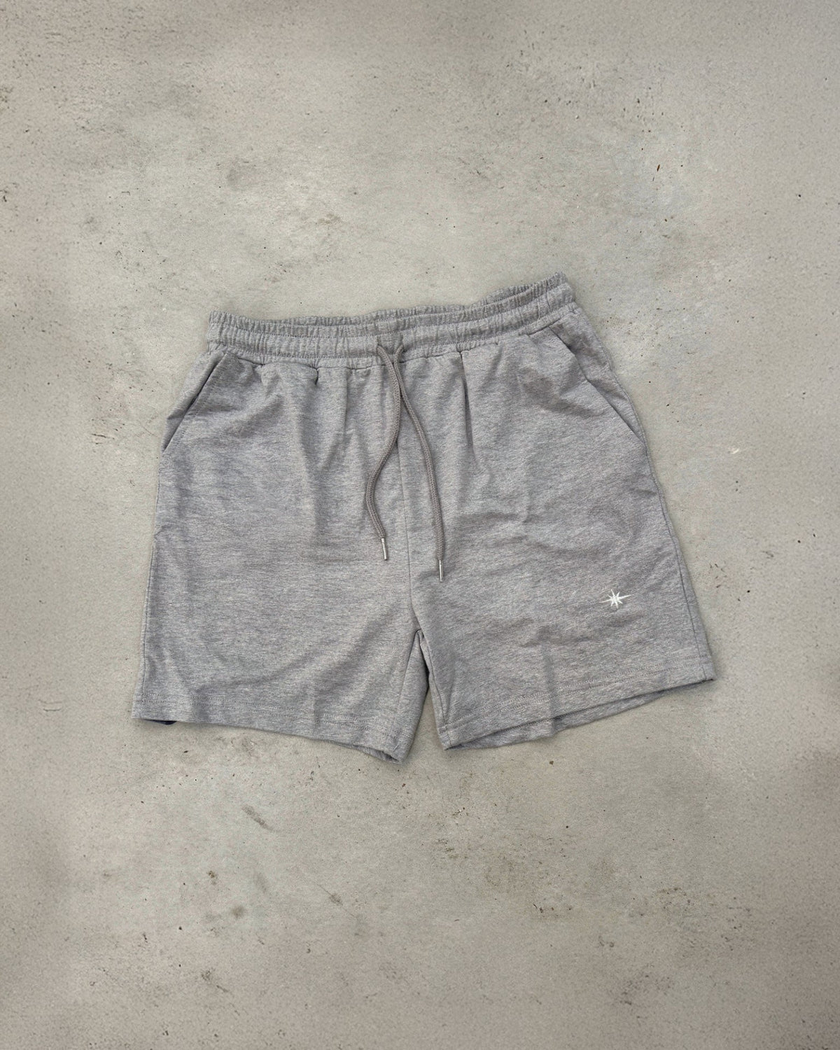 Ash grey Sol Dept. cotton gym shorts on a gray concrete surface