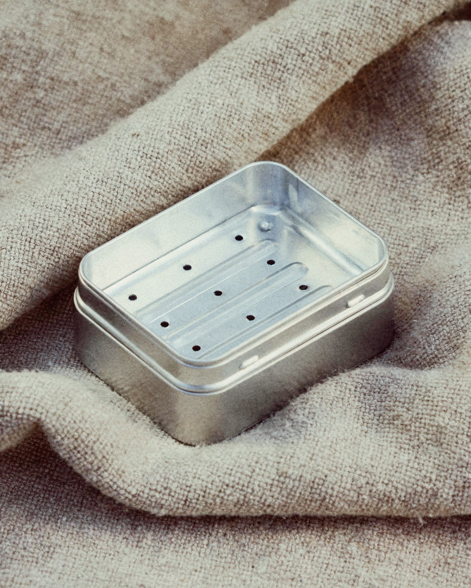 Metallic soap dish on a textured fabric background