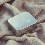 Metallic rectangular box with engraved design on a textured fabric background