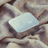 Metallic rectangular box with engraved design on a textured fabric background